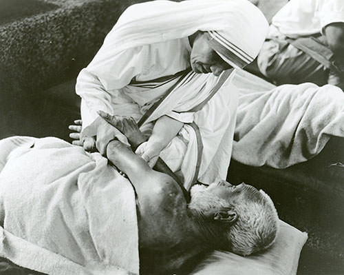 Mother Teresa taking care of a sick-man